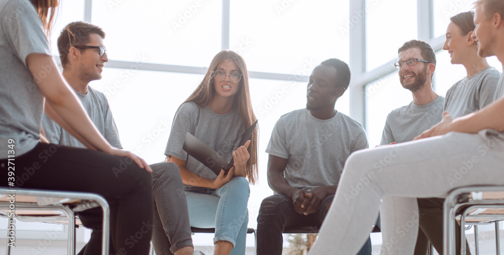 Obraz premium smiling speaker sitting in a circle of young people