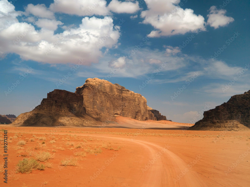 Wadi Rum characteristic landscape: rocky valley and 4x4 car tracks on the orange sand
