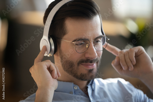 Close up image guy wear wireless headphones listen audio course improve english knowledge using online lesson, enjoy music relaxing at work. Hobby, modern technology usage for fun or learning concept photo