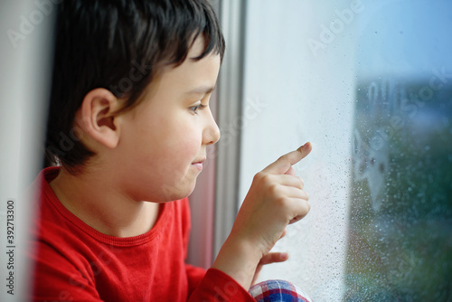 Принти на полотні Little sick boy in pajamas looking through window
