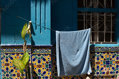 Photography Blue towell hanged in front a blue wall with design tiles