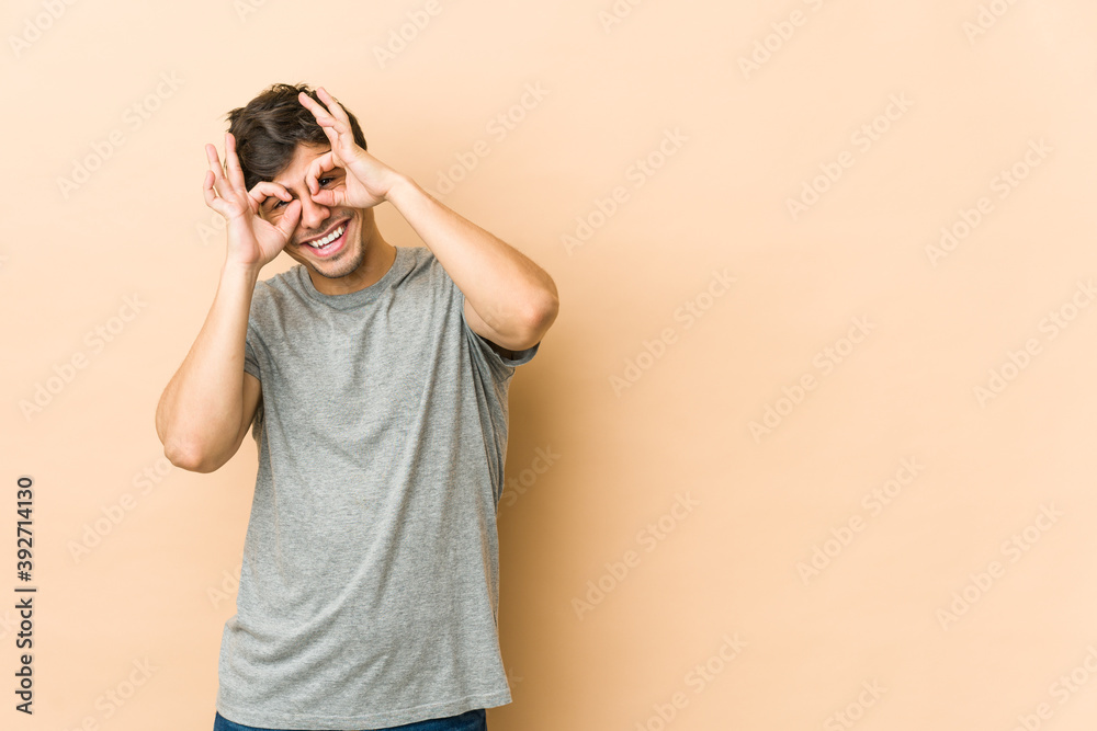 Young cool man showing okay sign over eyes Young cool man showing okay sign over eyes