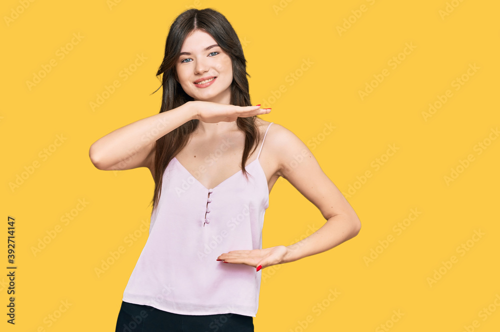 Young beautiful caucasian girl wearing casual clothes gesturing with hands showing big and large size sign, measure symbol. smiling looking at the camera. measuring concept. Young beautiful caucasian girl wearing casual clothes gesturing with hands showing big and large size sign, measure symbol. smiling looking at the camera. measuring concept.