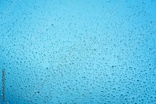 Drops of rain on window glass. Shallow DOF. Natural Blue Water background with Raindrops for sad mood and thoughts. Selective focus