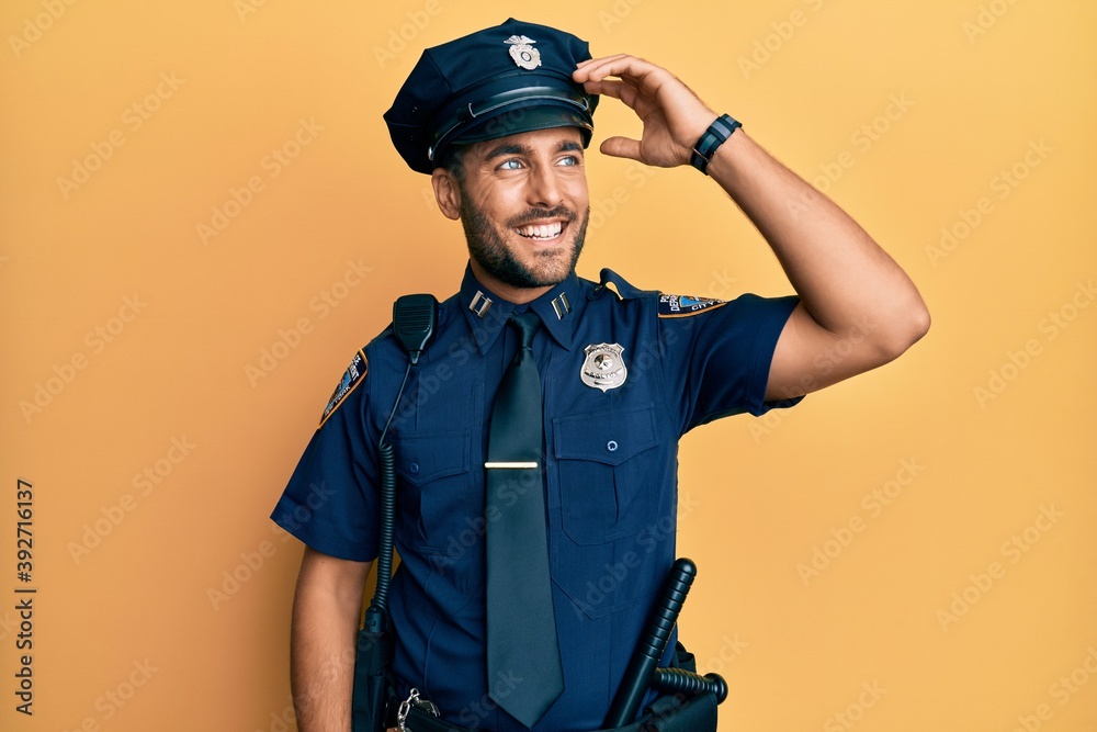 Handsome hispanic man wearing police uniform smiling confident touching hair with hand up gesture, posing attractive and fashionable Handsome hispanic man wearing police uniform smiling confident touching hair with hand up gesture, posing attractive and fashionable