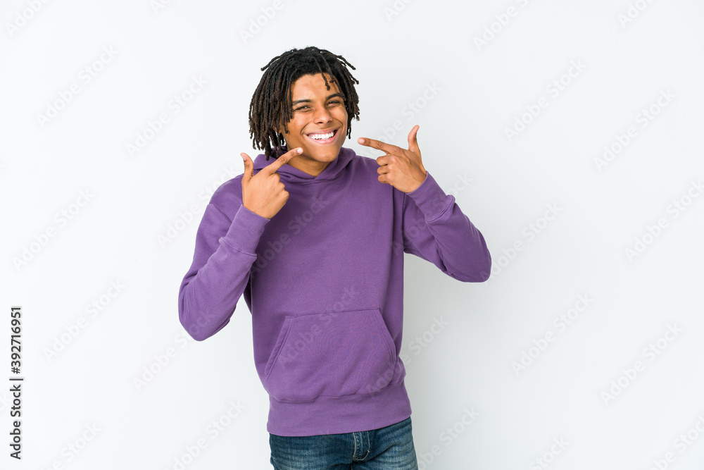 Young african american rasta man smiles, pointing fingers at mouth. Young african american rasta man smiles, pointing fingers at mouth.