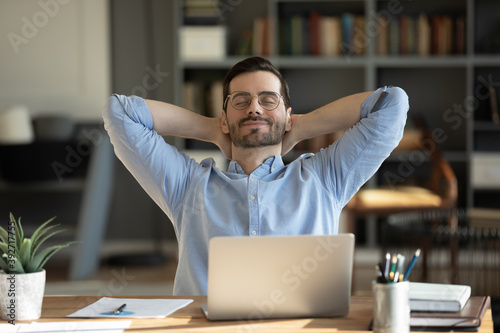 Fotografie Relaxed man take break from work put hands behind head lean on comfy chair closi