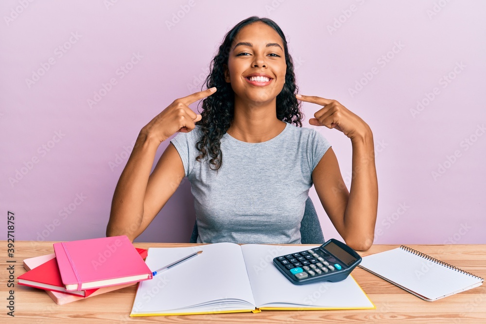 Young african american girl accountant working at the office smiling cheerful showing and pointing with fingers teeth and mouth. dental health concept. Young african american girl accountant working at the office smiling cheerful showing and pointing with fingers teeth and mouth. dental health concept.