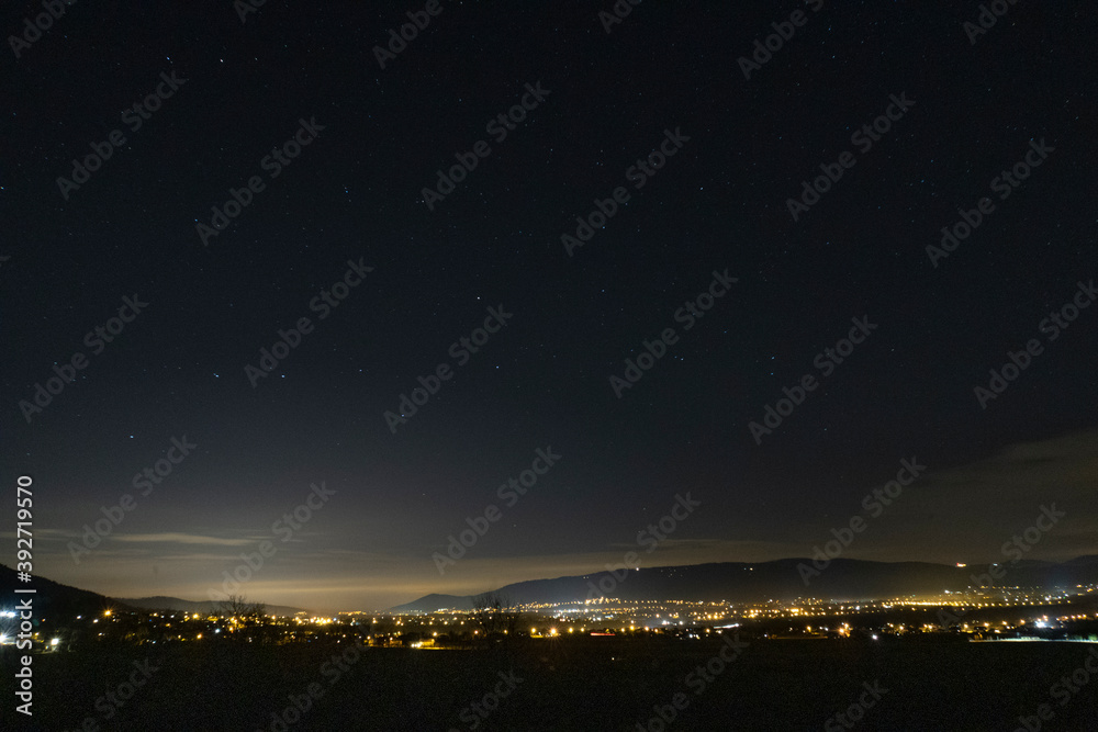 Night view of the starry sky with a city on the horizon