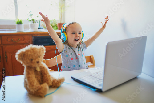 Toddler girl wearing eraphones with laptop photo