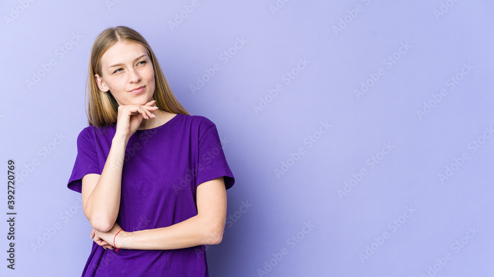 Young blonde woman isolated on purple background looking sideways with doubtful and skeptical expression. Young blonde woman isolated on purple background looking sideways with doubtful and skeptical expression.