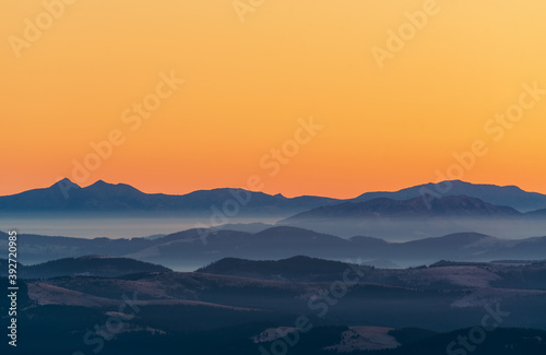 Beautiful  colorful mountain landscape in orange and blue tones with morning fog at sunrise.