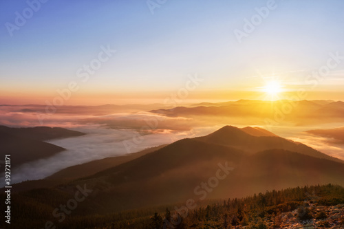 Magical colorful morning in the mountains with low clouds at sunrise.