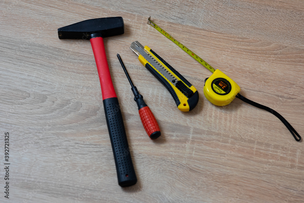 Hammer, screwdriver, measuring tape and technical knife on the table