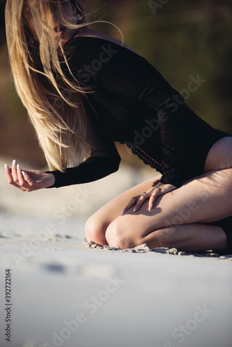 A young European girl with long straight hair on the beach, wears an expensive stylish black swimsuit