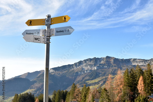 Signposts of hiking trails in region Amden in Switzerland. On the background there is autumn landscape with trees and mountains. 