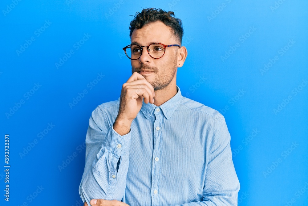 Handsome man with beard wearing casual clothes and glasses holding symbolic gun with hand gesture, playing killing shooting weapons, angry face Handsome man with beard wearing casual clothes and glasses holding symbolic gun with hand gesture, playing killing shooting weapons, angry face