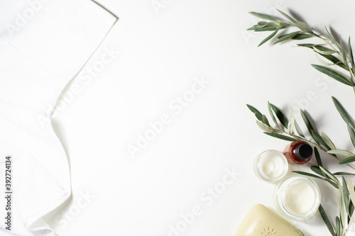 Natural organic cosmetics theme. A jar of cream, soap, a towel, a sprig of an olive tree are on a white background. Copy space.