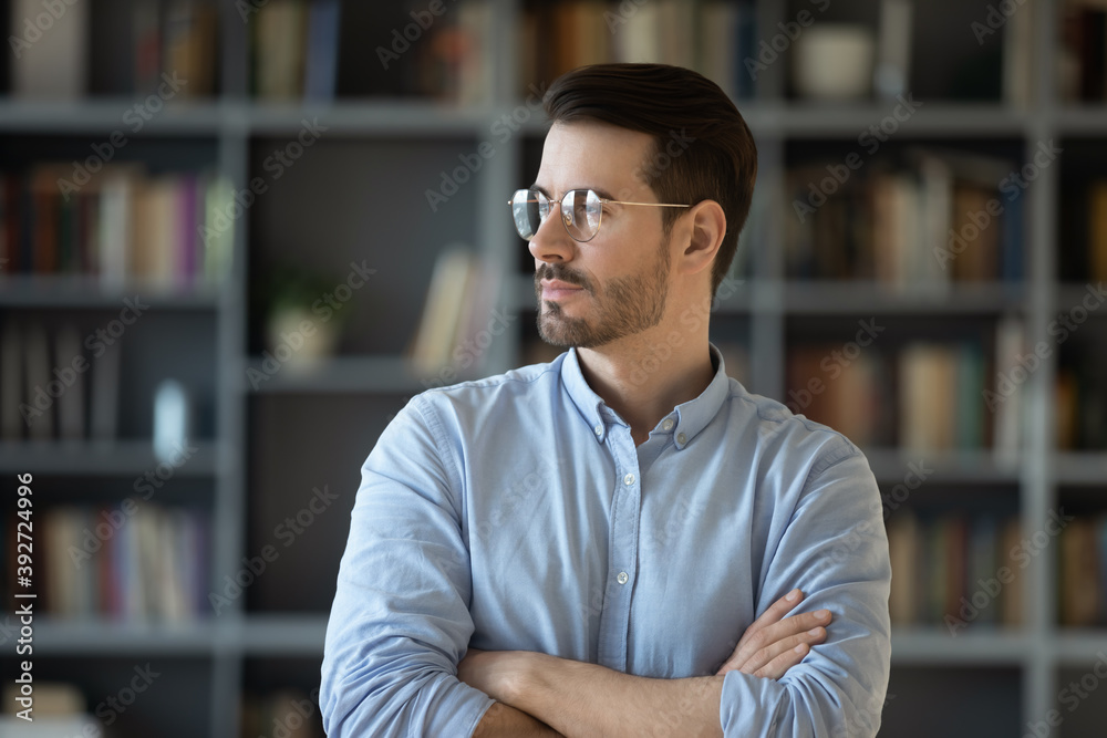 Head shot portrait confident business man standing with arms crossed on chest look into distance out window thinking about perspectives, career advance, planning, forecasting. Business vision concept Head shot portrait confident business man standing with arms crossed on chest look into distance out window thinking about perspectives, career advance, planning, forecasting. Business vision concept
