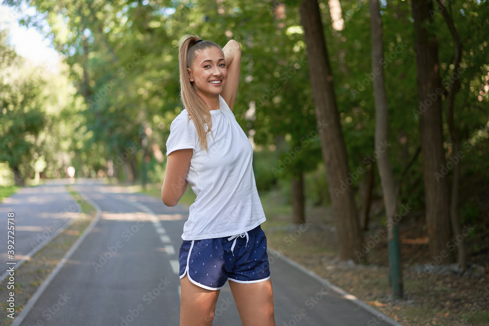 Woman runner stretching arms before exercising summer park morning Woman runner stretching arms before exercising summer park morning