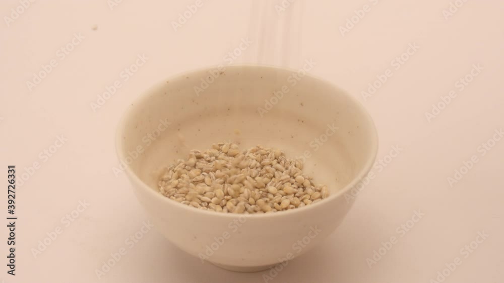 Healthy barley pouring into a white bowl.