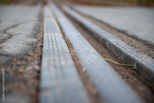 A long vintage track on a railway or railroad using a shallow depth of field. The permanent way of the steel track has multiple lines, gaps, within the heavy metal for allowing heat expansion. 