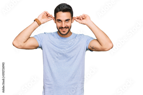 Young hispanic man wearing casual clothes smiling pulling ears with fingers, funny gesture. audition problem