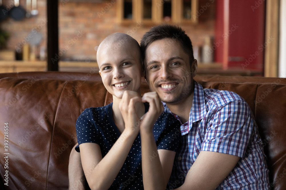 Love inspiring to live. Portrait of husband supporting hugging wife cancer  patient on sofa at home,