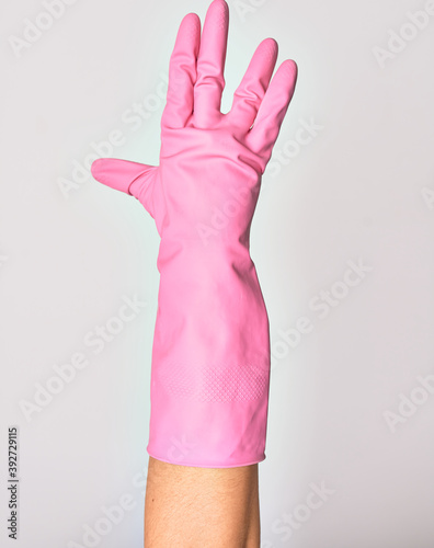 Hand of caucasian young woman wearing pink cleaning glove doing freaky star trek salutation over isolated white background