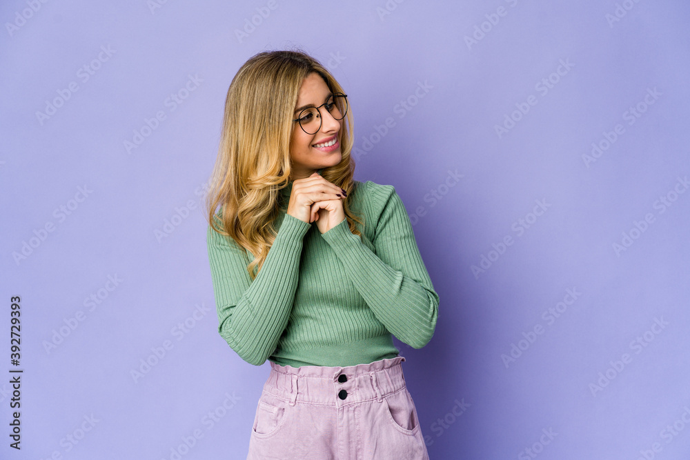 Young caucasian blonde woman keeps hands under chin, is looking happily aside. Young caucasian blonde woman keeps hands under chin, is looking happily aside.