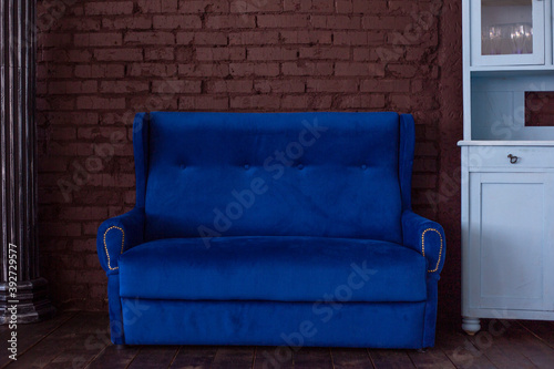 The blue sofa and sideboard stand against a red brick wall. Interior design