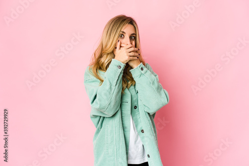 Young caucasian blonde woman shocked covering mouth with hands.