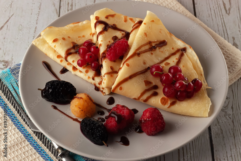 Pancakes with raspberries, currants and chocolate, decorated with a mint leaf Pancakes with raspberries, currants and chocolate, decorated with a mint leaf