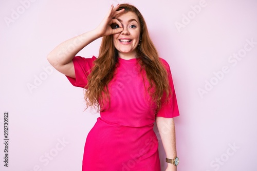 Young redhead woman wearing casual clothes smiling happy doing ok sign with hand on eye looking through fingers © Krakenimages.com