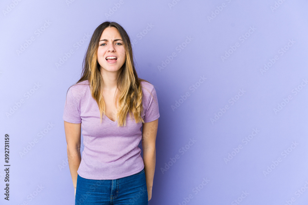 Young caucasian woman isolated on purple background shouting very angry, rage concept, frustrated. Young caucasian woman isolated on purple background shouting very angry, rage concept, frustrated.