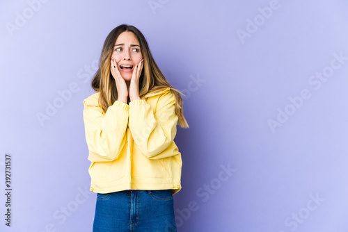 Young caucasian woman isolated on purple background scared and afraid.