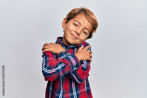 Valokuvatapetti Adorable latin kid wearing casual clothes hugging oneself happy and positive, smiling confident
