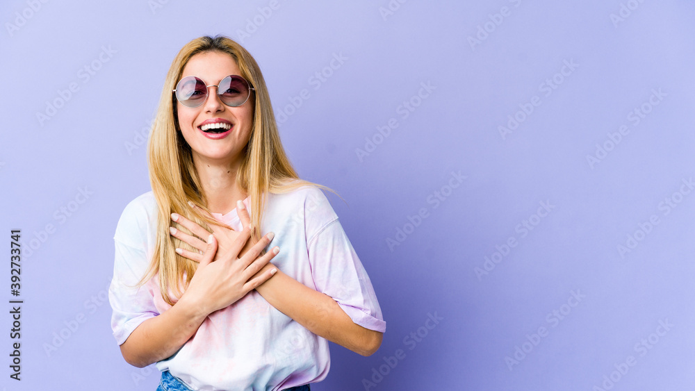 Young blonde caucasian woman laughs happily and has fun keeping hands on stomach. Young blonde caucasian woman laughs happily and has fun keeping hands on stomach.