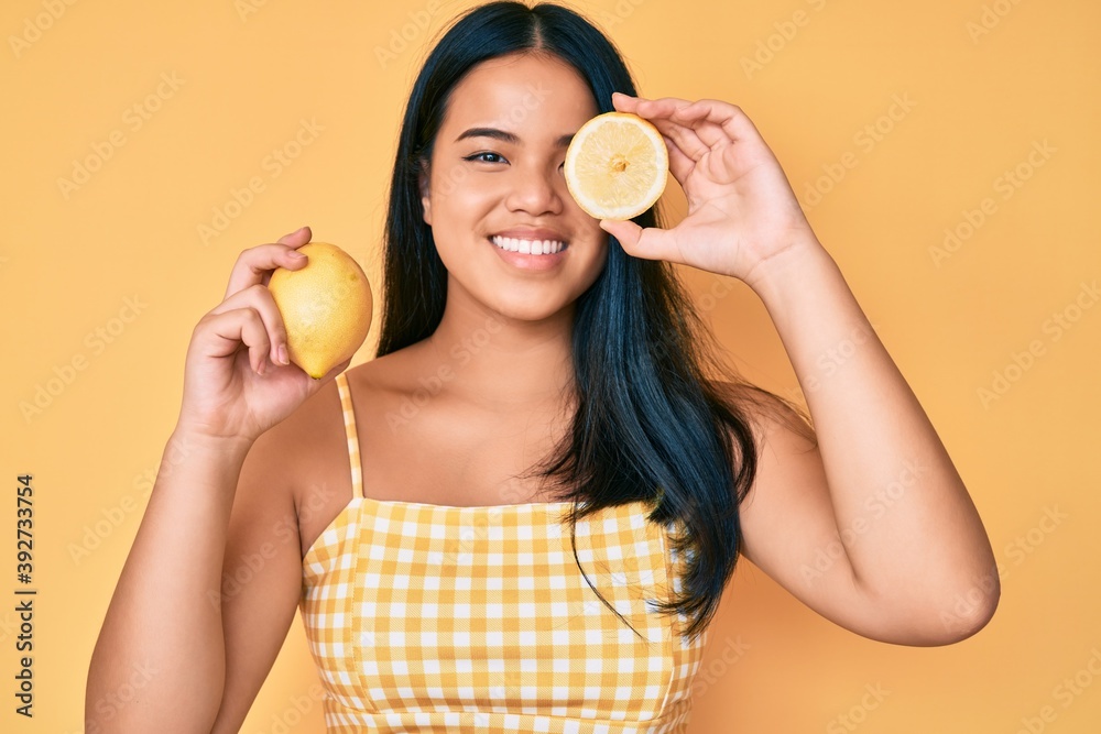 Young beautiful asian girl holding lemon smiling with a happy and cool smile on face. showing teeth. Young beautiful asian girl holding lemon smiling with a happy and cool smile on face. showing teeth.