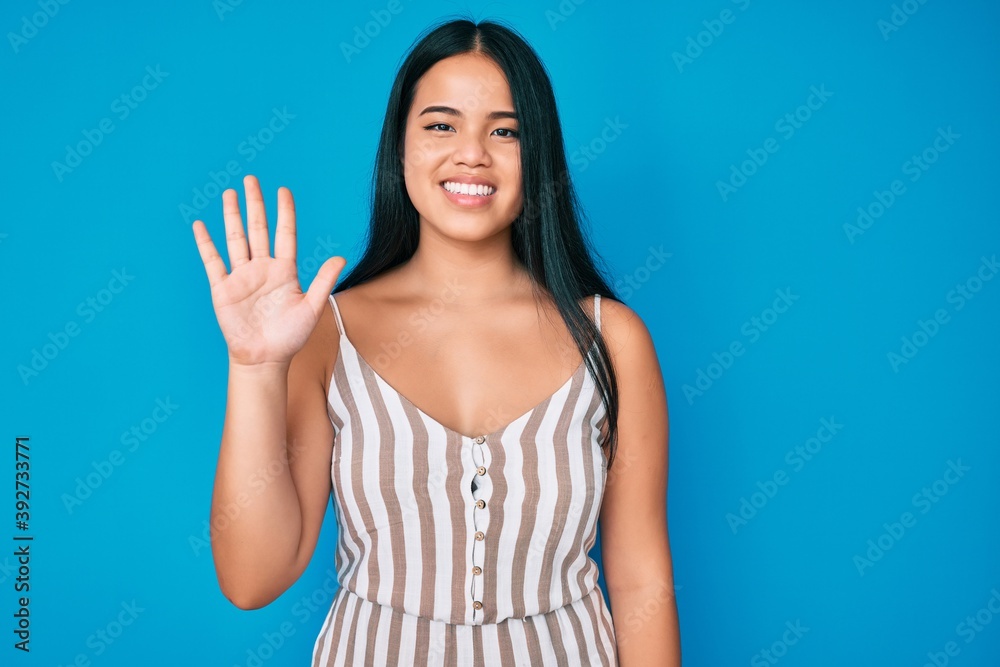 Young beautiful asian girl wearing casual clothes showing and pointing up with fingers number five while smiling confident and happy. Young beautiful asian girl wearing casual clothes showing and pointing up with fingers number five while smiling confident and happy.