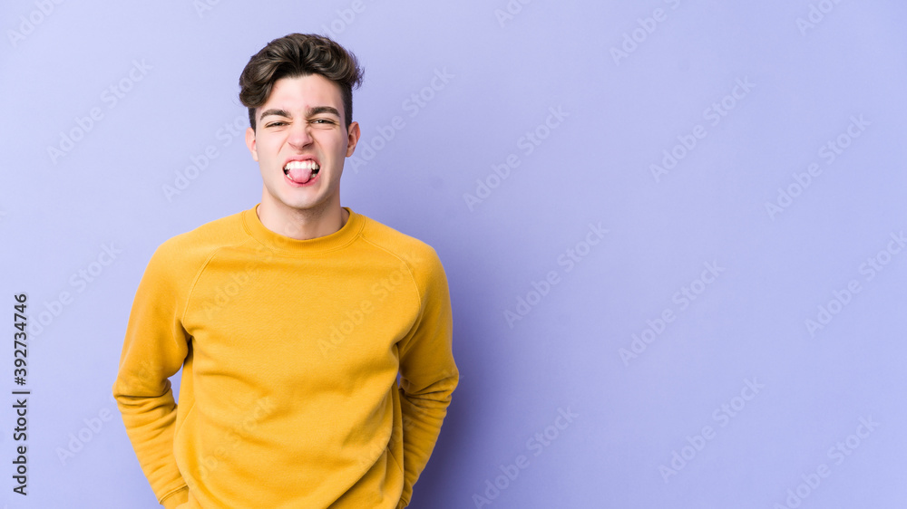 Young caucasian man isolated on purple background funny and friendly sticking out tongue. Young caucasian man isolated on purple background funny and friendly sticking out tongue.