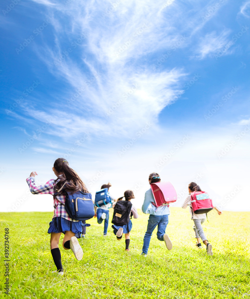 rear view of elementary school kids running on the grass rear view of elementary school kids running on the grass