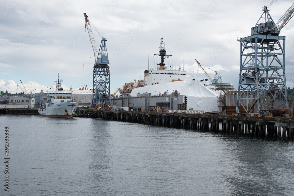 Cranes in port at the harbor with white ship on a cloudy day