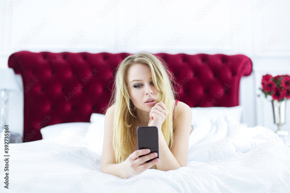 Chic blonde woman in luxury white with red bedroom. Rich expensive interior. Chic blonde woman in luxury white with red bedroom. Rich expensive interior.