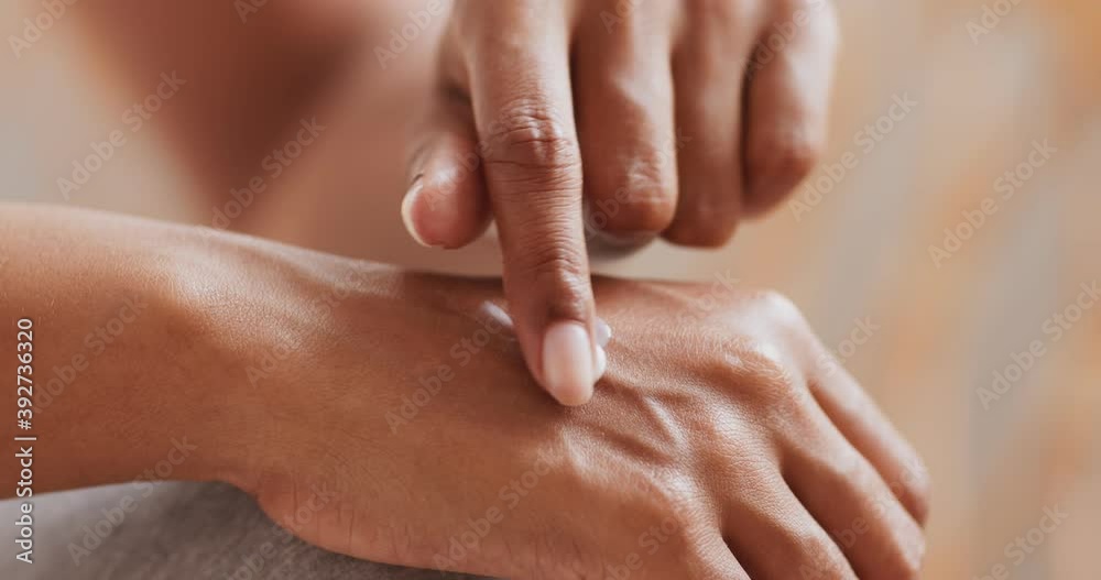 Close up of black woman applying hand cream, making daily beauty treatment at home, slow motion Close up of black woman applying hand cream, making daily beauty treatment at home, slow motion