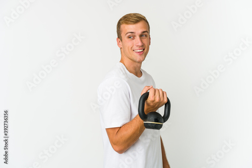 Young caucasian man holding a kettlebell isolated on white background