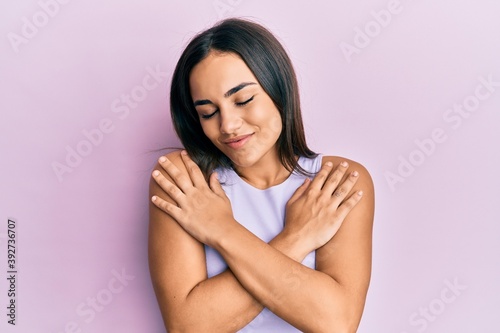 Young brunette woman wearing casual clothes hugging oneself happy and positive, smiling confident. self love and self care