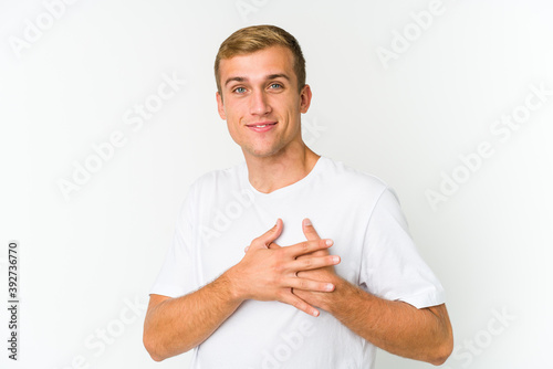 Young caucasian handsome man has friendly expression, pressing palm to chest. Love concept.