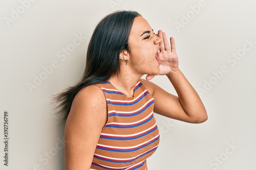 Young brunette woman wearing casual clothes shouting and screaming loud to side with hand on mouth. communication concept. © Krakenimages.com