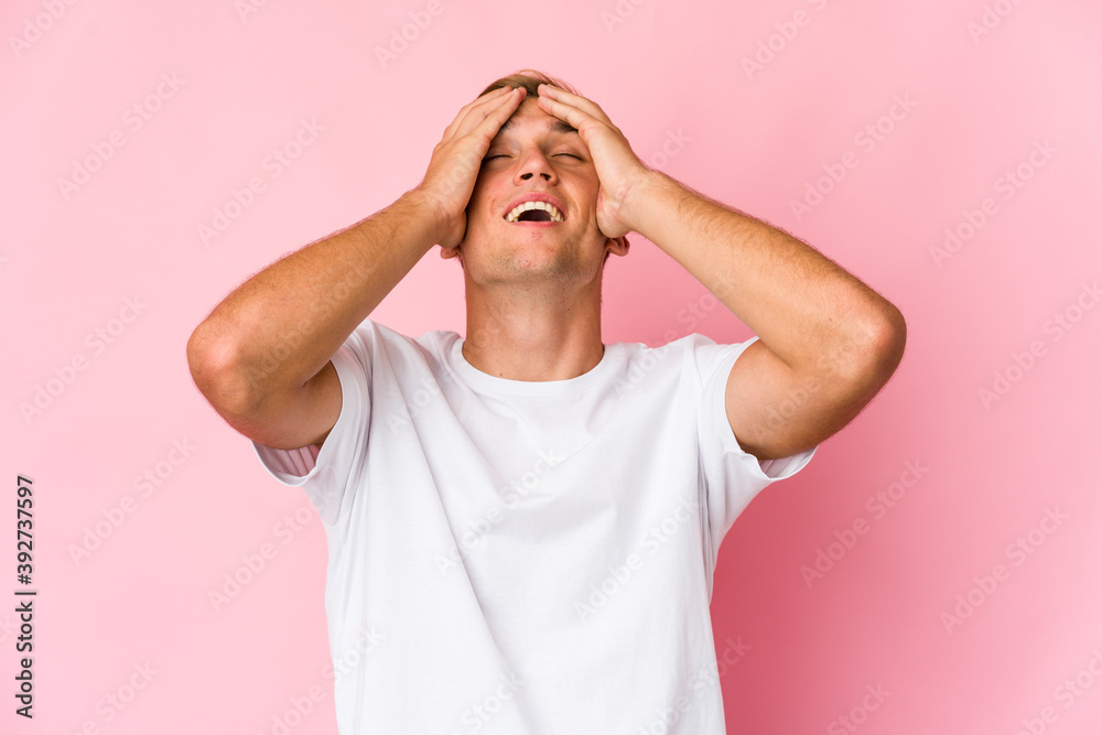 Young caucasian handsome man laughs joyfully keeping hands on head. Happiness concept. Young caucasian handsome man laughs joyfully keeping hands on head. Happiness concept.